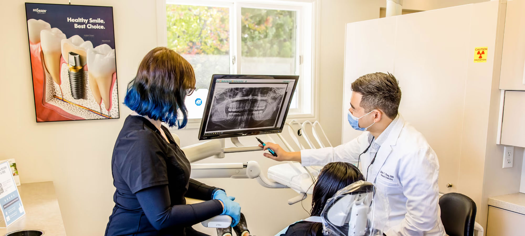 The image shows a modern dental clinic interior with various pieces of equipment, including a dental chair and an X-ray machine.